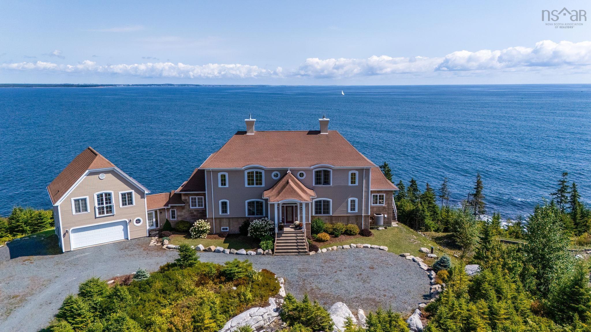 View of front of house featuring driveway, a chimney, and a water view
