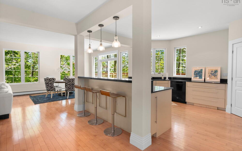 Kitchen featuring dark countertops, dishwasher, light wood finished floors, a kitchen breakfast bar, and decorative light fixtures