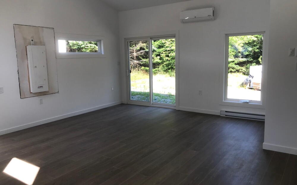 Spare room featuring plenty of natural light, vaulted ceiling, baseboard heating, dark wood-type flooring, and a wall mounted AC