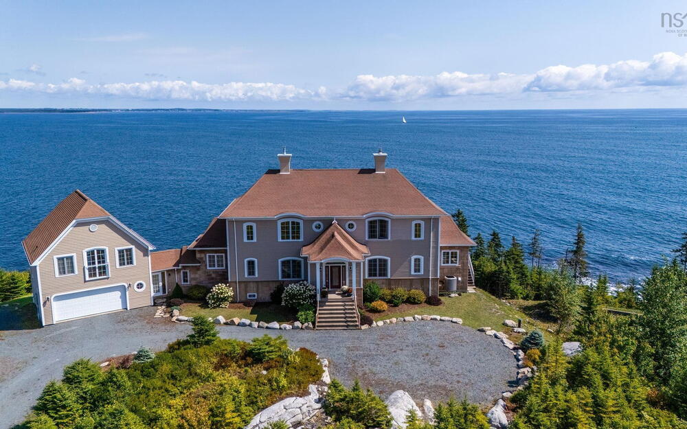 View of front of house featuring driveway, a chimney, and a water view
